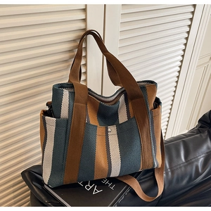 Detail of large tote bag showing retro contrast vertical stripes and brown shoulder strap