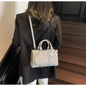 Silver metallic pleated tote bag with round pouch shown on a model in a modern setting