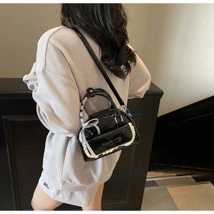 Detail of black glossy handbag with white lace trim and bow accent on model