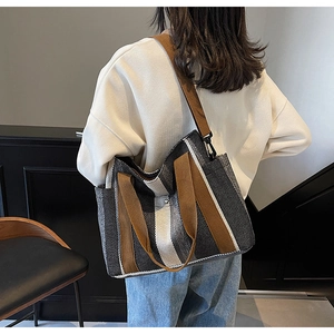 Detail of high-capacity striped canvas tote with brown straps and side pocket detail