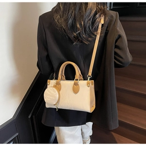 Detail of minimalist cream and brown crossbody bag with a round hanging coin purse