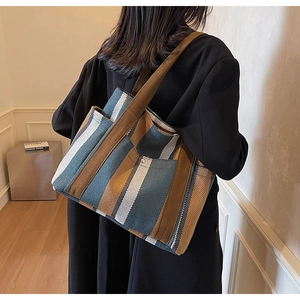 Detail of large striped tote bag with wide shoulder strap and metal buckle closure