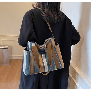 Detailed back view of a vertical striped canvas tote bag with brown woven handles
