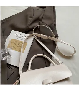Détail du sac bandoulière blanc cassé avec sangle réglable et boucles métalliques