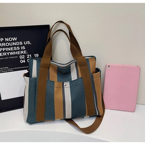 Detail of canvas tote bag showing striped pattern, side pocket and durable metal hardware