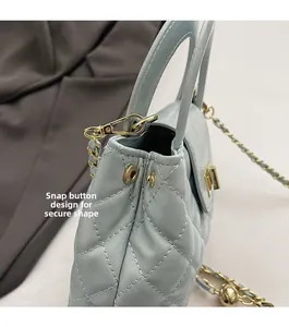 Detail of light blue quilted handbag side snap button design and golden chain strap