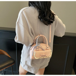 Detail of pink mini bag featuring ribbon handles, lace trim, and bow decoration