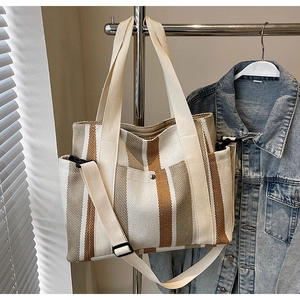 Detailed view of striped canvas tote bag with adjustable strap and metal snap pocket