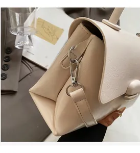 Détail d'un sac à main beige avec fermoir rotatif argenté et texture en cuir de qualité