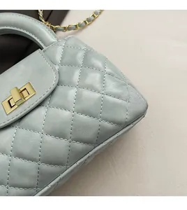 Detail of light blue quilted crossbody bag with gold twist lock and metal chain strap