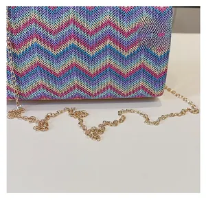 Detailed macro shot of the colorful zigzag woven texture and gold chain on the bag