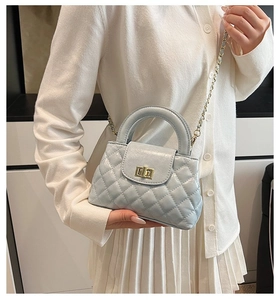 Detail of light blue quilted crossbody bag with golden turn-lock and chain strap