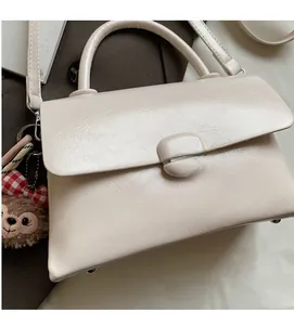 Gros plan du sac à main crème en cuir avec breloque hérisson et texture souple