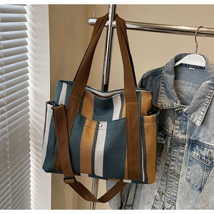 Detailed view of vertical striped canvas tote bag with front buckle pocket and wide strap