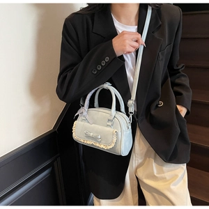 Light blue bowling bag with bow and lace detail styled by model on stairs