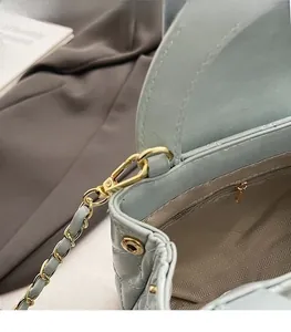 Macro detail of golden hardware buckle and herringbone lining on mint quilted bag