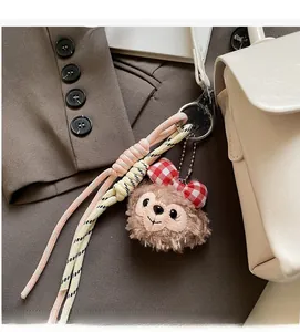 Gros plan du pendentif ours en peluche avec nœud à carreaux pour accessoire de sac