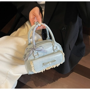 Detail of light blue handbag with lace trim, bow pocket, and gingham scarf handle