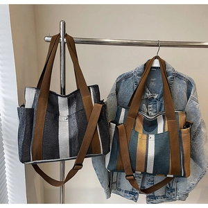 Close-up of striped canvas tote bags with adjustable straps hanging on a metal rack