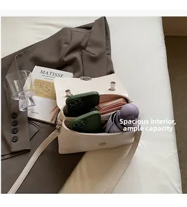 Intérieur spacieux d'un sac bandoulière crème contenant téléphones, portefeuille et parapluie