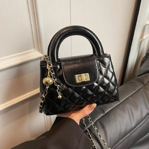 Close-up of black quilted leather handbag with gold metal clasp and chain strap detail