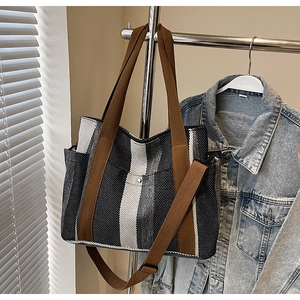 Hanging canvas tote bag with vertical stripes, brown straps, and side pocket detail