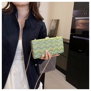 Close-up of green and blue woven pattern on luxury chain handbag with gold buckle