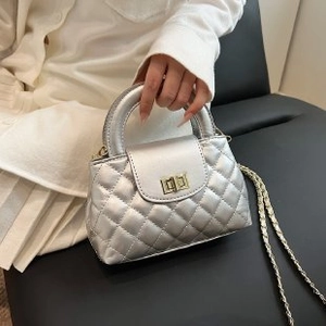 Detailed close-up of a silver quilted mini bag featuring golden chain and twist lock