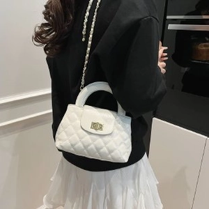 Detail of white quilted crossbody bag with gold twist lock and pearl chain strap