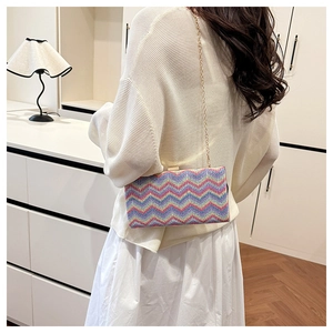 Detail of colorful zigzag woven crossbody bag with gold chain strap on a model