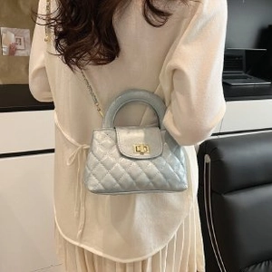 Detail shot of light blue quilted leather bag with gold hardware and metal chain strap
