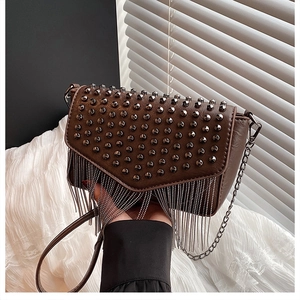 Detailansicht der braunen Ledertasche mit Metallnieten und Kettenfransen-Details