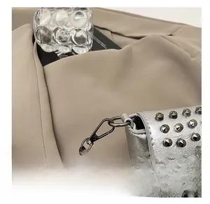 Details einer silbernen Tasche mit dunkelgrauen Kettenhaken und Nietenverzierung