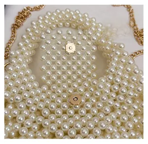 Detail of handmade pearl handbag featuring a secure gold magnetic clasp and metal chain