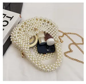 Detail view of pearl beaded handbag interior showing storage for phone and cosmetics