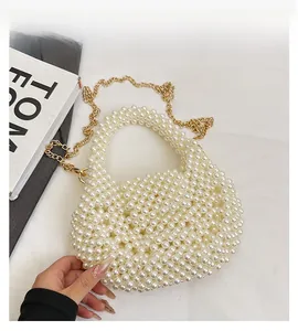 Detailed close-up of handmade pearl woven handbag with a fine gold metal chain strap