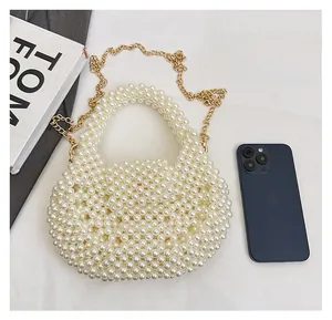 Detailed close-up of white pearl beaded handbag with gold metal chain strap and top handle