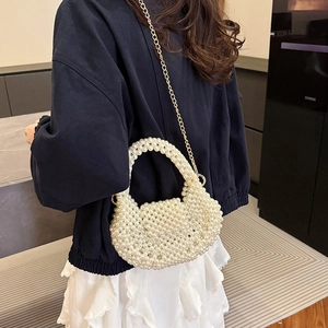 Elegant white pearl beaded handbag with gold chain strap shown on a female model