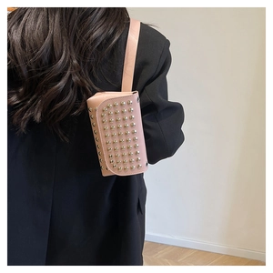 Detail of pink crossbody bag featuring silver stud embellishments on smooth leather surface