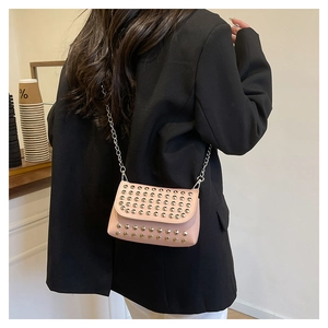 Detailed close-up of light pink crossbody bag featuring silver studs and metal chain strap
