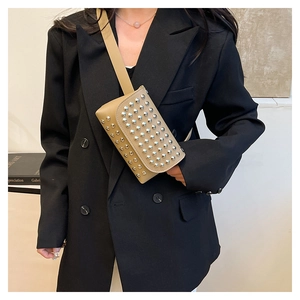 Detail of beige leather bag with silver studs worn over a black blazer for urban style