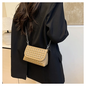 Detail of light khaki square bag with silver studs and chain strap on a black blazer