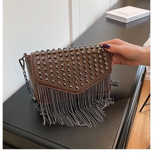 Detail einer braunen PU-Leder Umhängetasche mit Nieten und langen Kettenquasten