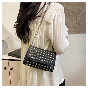 Detail of black punk crossbody bag featuring silver semi-circular rivets and metal chain strap