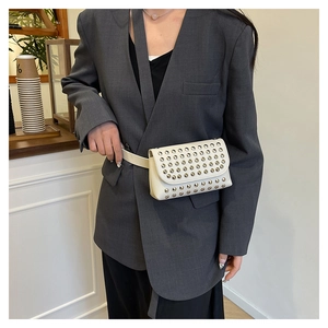 Detail of cream leather waist bag with silver studs worn over an oversized blazer