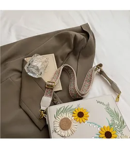 Detailed embroidery of sunflower and floral patterns on a white leather shoulder bag