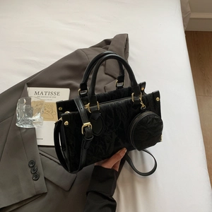 Minimalist black tote bag with gold hardware and small round coin purse on grey blazer