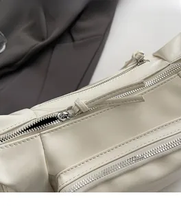 Detail shot of smooth double zipper design and leather texture on a beige biker bag