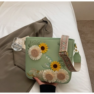Detail of floral embroidery on mint green leather square bag with a wide strap