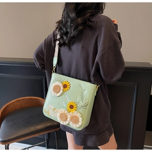 Detail of pistachio green crossbody bag featuring exquisite sunflower embroidery and wide strap
